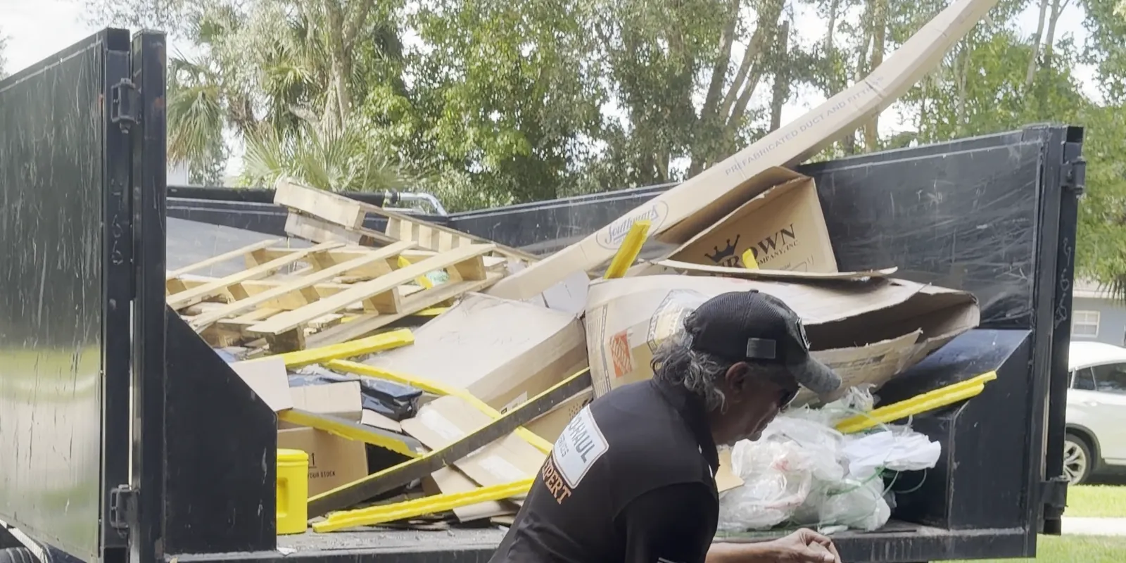 Eco Haul crew member loading flattened boxes, pallets and packing material into the dump trailer