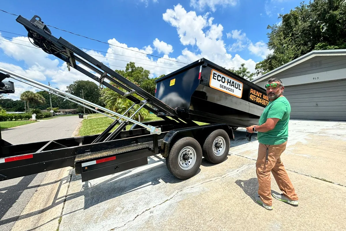 Eco Haul roll off dumpster coming down off the tilt trailer onto a customer's driveway
