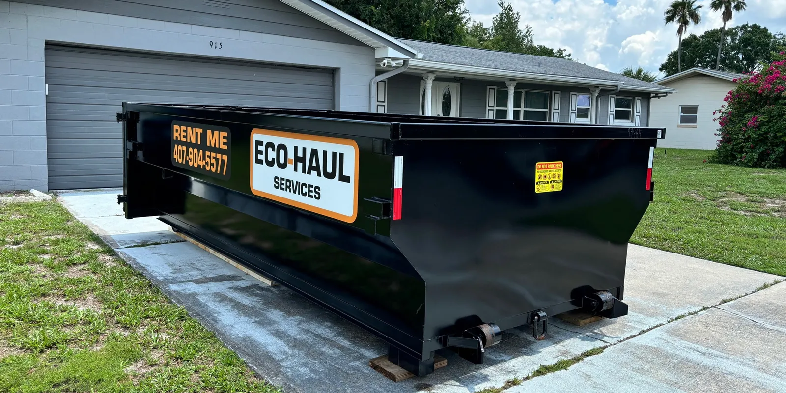 Eco Haul 14 yard dumpster on wooden planks on a driveway next to the garage