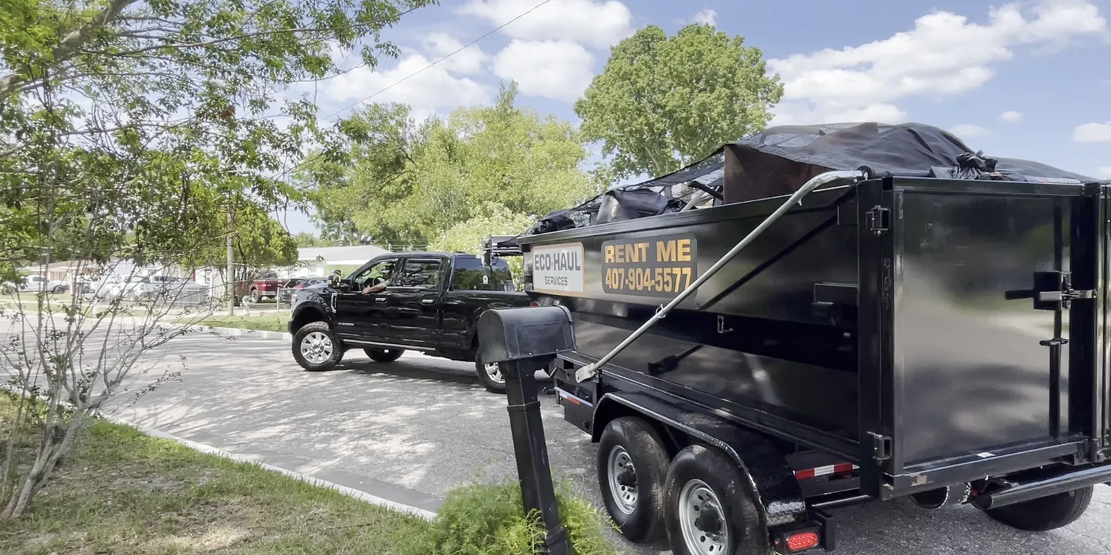 Eco Haul truck and covered dump trailer parked on a residential street in front of a house