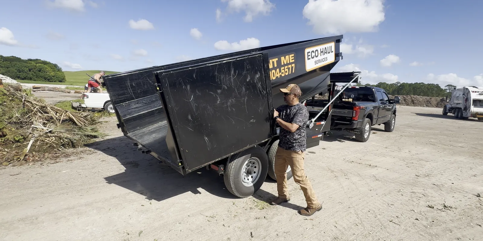 Eco Haul crew member closing the tailgate of the dump trailer at the disposal yard after tipping a load